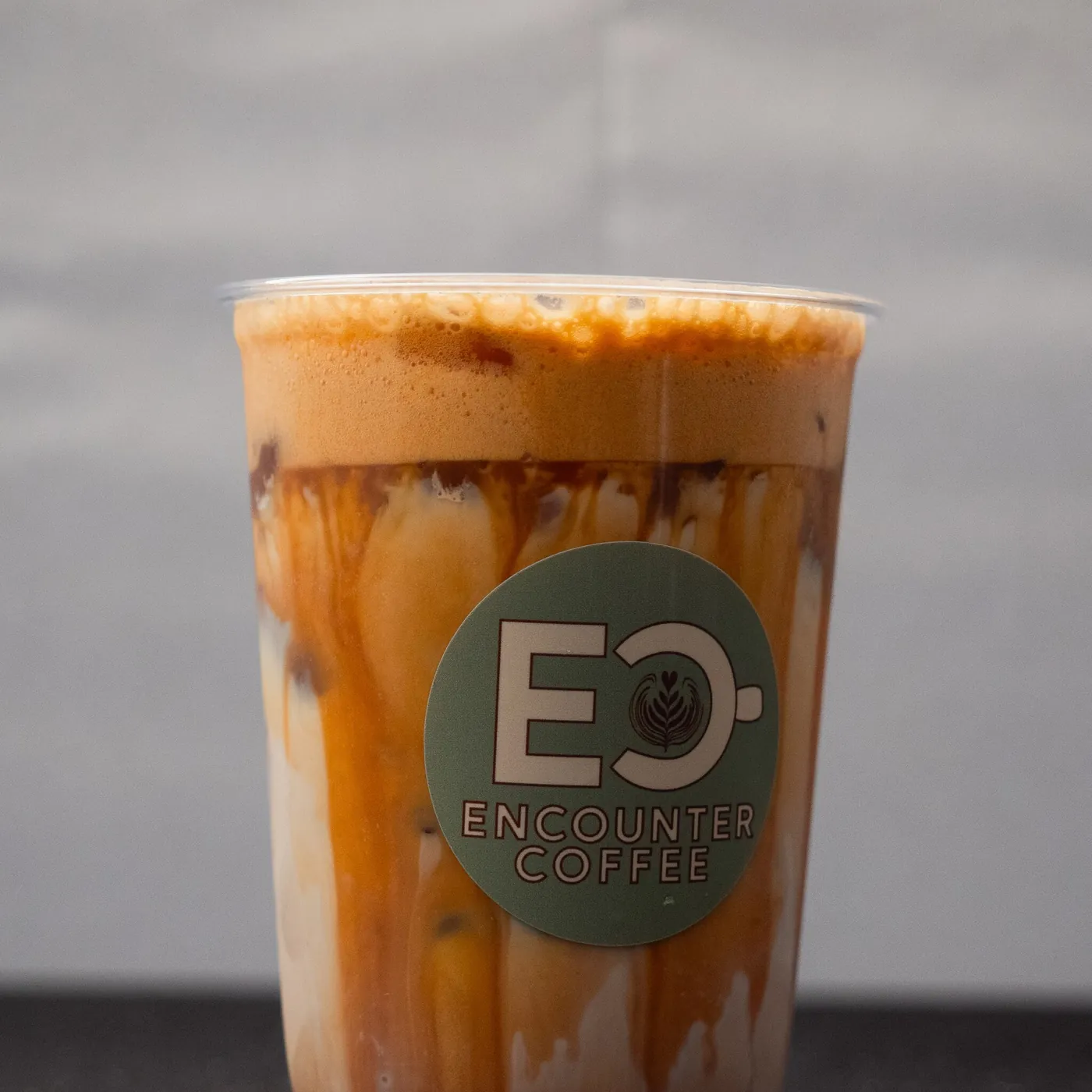 Caramel iced latte in an Encounter Coffee cup, made to order at a coffee cart catering event